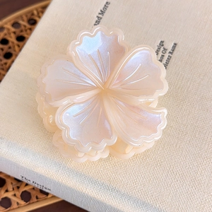 Dettaglio della molletta per capelli a fiore con finitura perlata su un libro