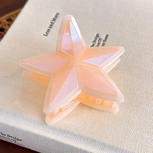 Detalle macro de una pinza para el cabello de estrella rosa perlado sobre fondo de libro