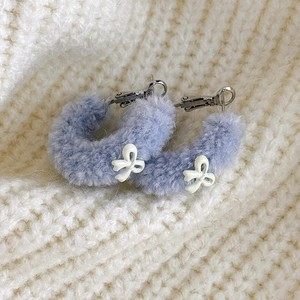 Gros plan de boucles d'oreilles en peluche lavande avec petit nœud blanc décoratif