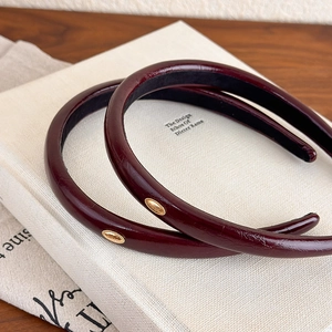 Retro burgundy leather headbands with gold metal oval detail on a white book base