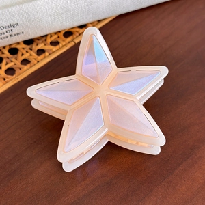 Pinza para el pelo con forma de estrella y acabado nacarado en mesa de madera