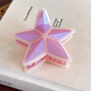 Primer plano de pinza de estrella rosa con facetas púrpuras iridiscentes sobre libro