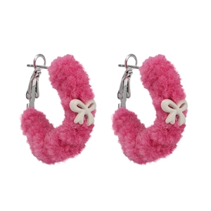 Créoles en peluche rose avec petits nœuds blancs sur une base minimaliste en argent