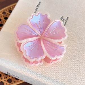 Dettaglio della pinza per capelli a fiore rosa perlato con bordi bianchi su un libro