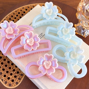 Détail macro de pinces à cheveux géométriques avec motifs floraux nacrés aux tons pastel