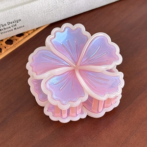 Dettaglio molletta per capelli a fiore con sfumatura perlata rosa e blu su legno