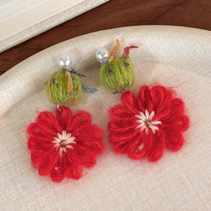Close-up of handmade red crochet flower earrings with pearls on a decorative tray