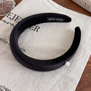 Detailed macro view of black velvet headband with a single pearl and hand made label