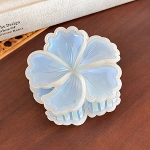 Dettaglio di un fermaglio per capelli a fiore azzurro con finitura cangiante