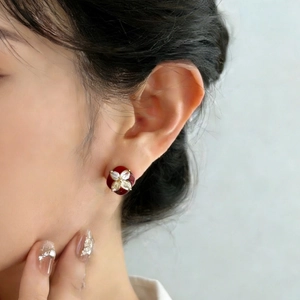 Boucles d'oreilles fleur à quatre pétales bordeaux avec zircons portées par un modèle