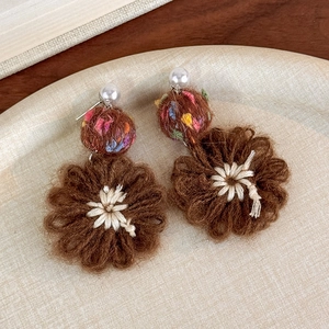 Detail of handmade knit flower earrings with colorful yarn balls and white pearls