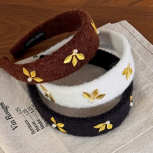 Detail of wool fabric headbands with golden leaves, pearls and handmade label