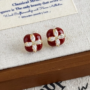Boucles d'oreilles rétro en émail bordeaux et zircons sur une boîte à bijoux en bois