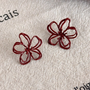 Macro shot of retro wine red hollow flower earrings with double layered petals