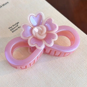 Gros plan d'une pince à cheveux en résine nacrée rose avec motif fleur de rose