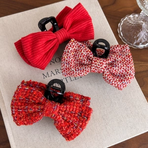 Three elegant red knitted and tweed bow hair claw clips for women on a cozy background