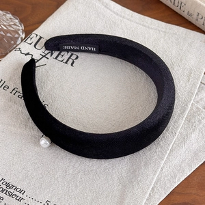 Vintage black velvet padded headband with pearl accent on elegant linen background