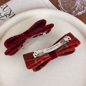 Dettaglio di fermagli per capelli a fiocco in velluto rosso e tessuto a quadretti