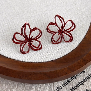 Detailed close-up of wine red hollow floral earrings with elegant petal design and metal finish