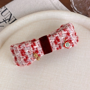 Dettaglio del fermaglio a fiocco in tweed rosso con pendenti a forma di arachide e carattere