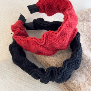Detailed view of red and black pleated knitted headbands with thick autumn winter textures