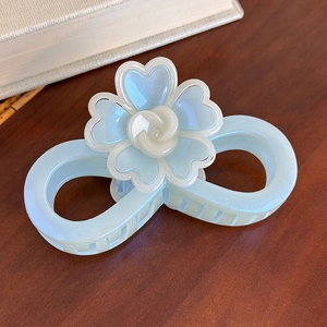 Détail d'une pince à cheveux bleue nacrée avec fleurs sur une surface en bois foncé
