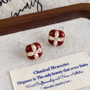 Détail de boucles d'oreilles trèfle émaillées rouges avec incrustation de zircon