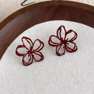 Detail of burgundy hollow flower stud earrings with vintage matte metallic texture