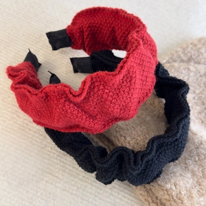 Detail of red and black knitted headbands showing wavy pleated texture and satin ends