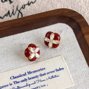 Gros plan de boucles d'oreilles trèfle en émail rouge et zircons sur plateau