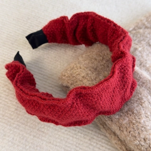 Close-up of red ruffled knit headband with detailed woolen texture and protective ends