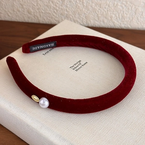 Detail of burgundy velvet headband showing a single pearl, gold buckle and handmade label