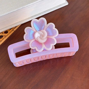 Vue détaillée de la pince à cheveux florale irisée avec rose violette sur bois
