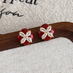 Détails macro des boucles d'oreilles émail rouge et zircone sur bois brun