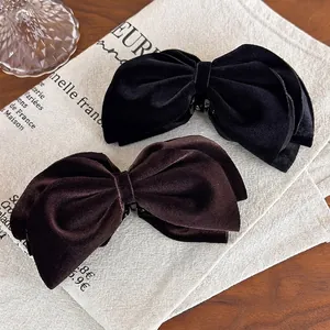 Velvet bow banana hair clips in black and dark brown on vintage beige linen fabric