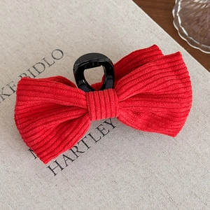 Macro detail of red corduroy bow hair claw clip showing vertical ribbed texture