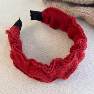 Close-up of red ruffled knit headband with textured waffle fabric for autumn winter style
