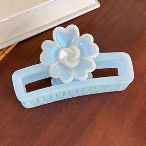Détail de la pince à cheveux bleue avec motif floral et finition nacrée sur bois