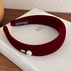 Detail of red velvet headband with pearl accent and handmade label on book