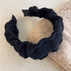 Close-up of black pleated knitted headband showing detailed texture and scrunchie design