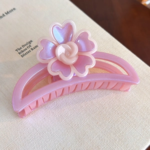 Gros plan sur une pince à cheveux fleur rose nacré sur un fond de page de livre élégant