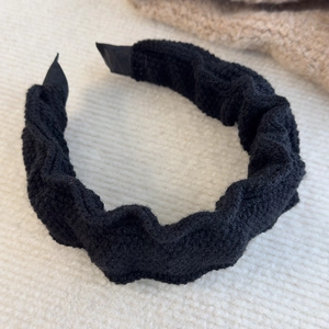 Detail of black pleated scrunchie headband with soft knitted texture and anti-slip ends