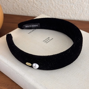 Close-up of black velvet padded headband with white pearl and gold metal detail