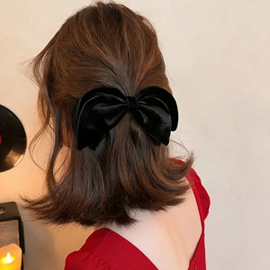 Elegant black velvet bow banana clip for high ponytail styling on textured background