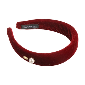 Macro detail of wine red velvet headband with white faux pearl and golden metal accent