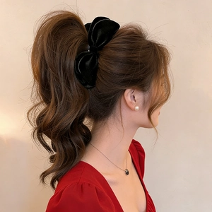 Detail view of a black velvet bow hair clip styled on a high ponytail for women
