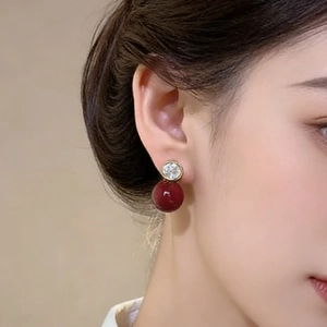 Boucles d'oreilles dorées avec perle rouge foncé polie et clou en zircon étincelant