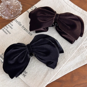 Close-up of premium velvet bow banana clips in dark brown and black on linen