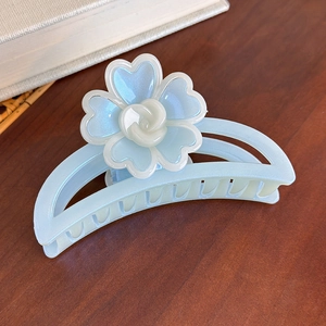 Vue détaillée d'une pince à cheveux bleu clair ornée d'une fleur aux reflets nacrés