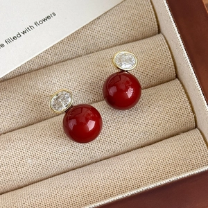 Gros plan de boucles d'oreilles perles rouges avec zircon ovale dans un coffret